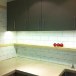 concrete worktop / deck mounted taps / plywood shelf / brick pattern tiling / olive cupbd doors